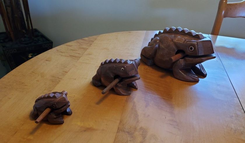 Three wooden rasp instruments in the shape of frogs, each a different size.
