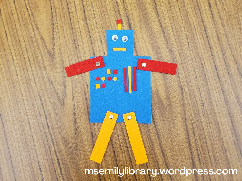 Felt robot craft in blue, red, and orange, with gold brads holding on the arms and legs