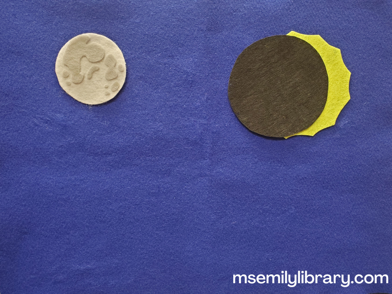 Flannelboard pieces of a realistic white moon with light gray craters, a bright yellow sun with short rays, and a black circle that would cover the sun but show the rays. The black circle is 80% covering the sun in this picture.